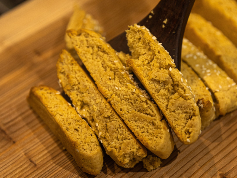 A plate of golden-brown Greek paximadia biscuits, twice-baked for a crispy texture, served with a cup of coffee on a rustic wooden table.
